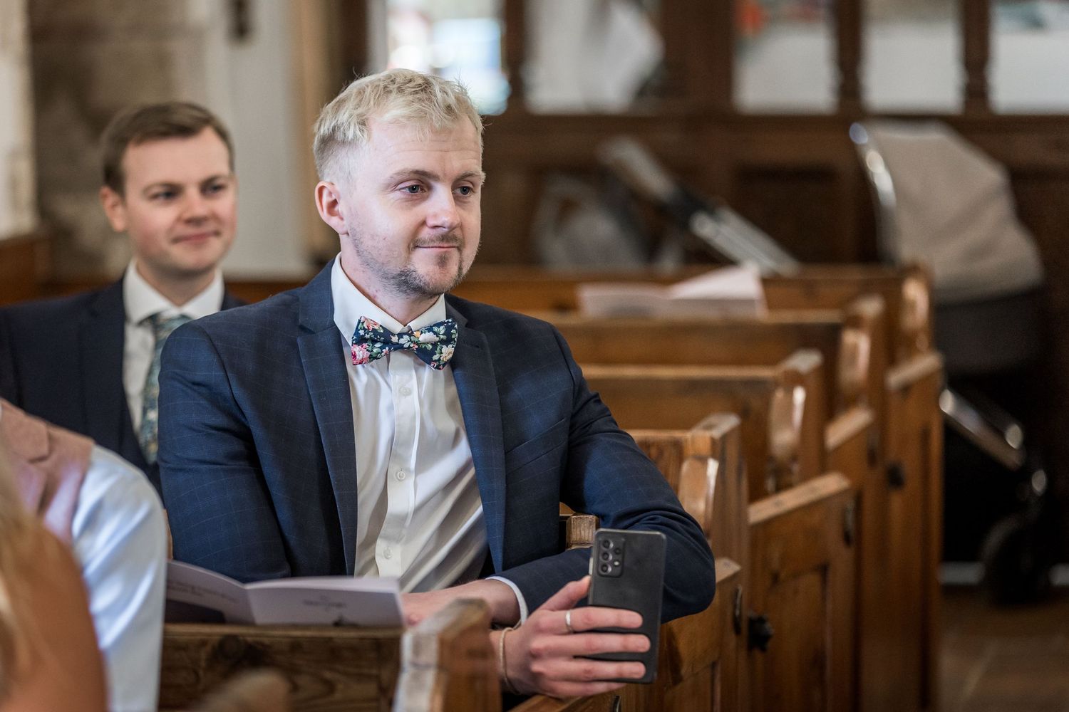 Wedding guests seated in wooden pews inside a historic church with gothic architecture.