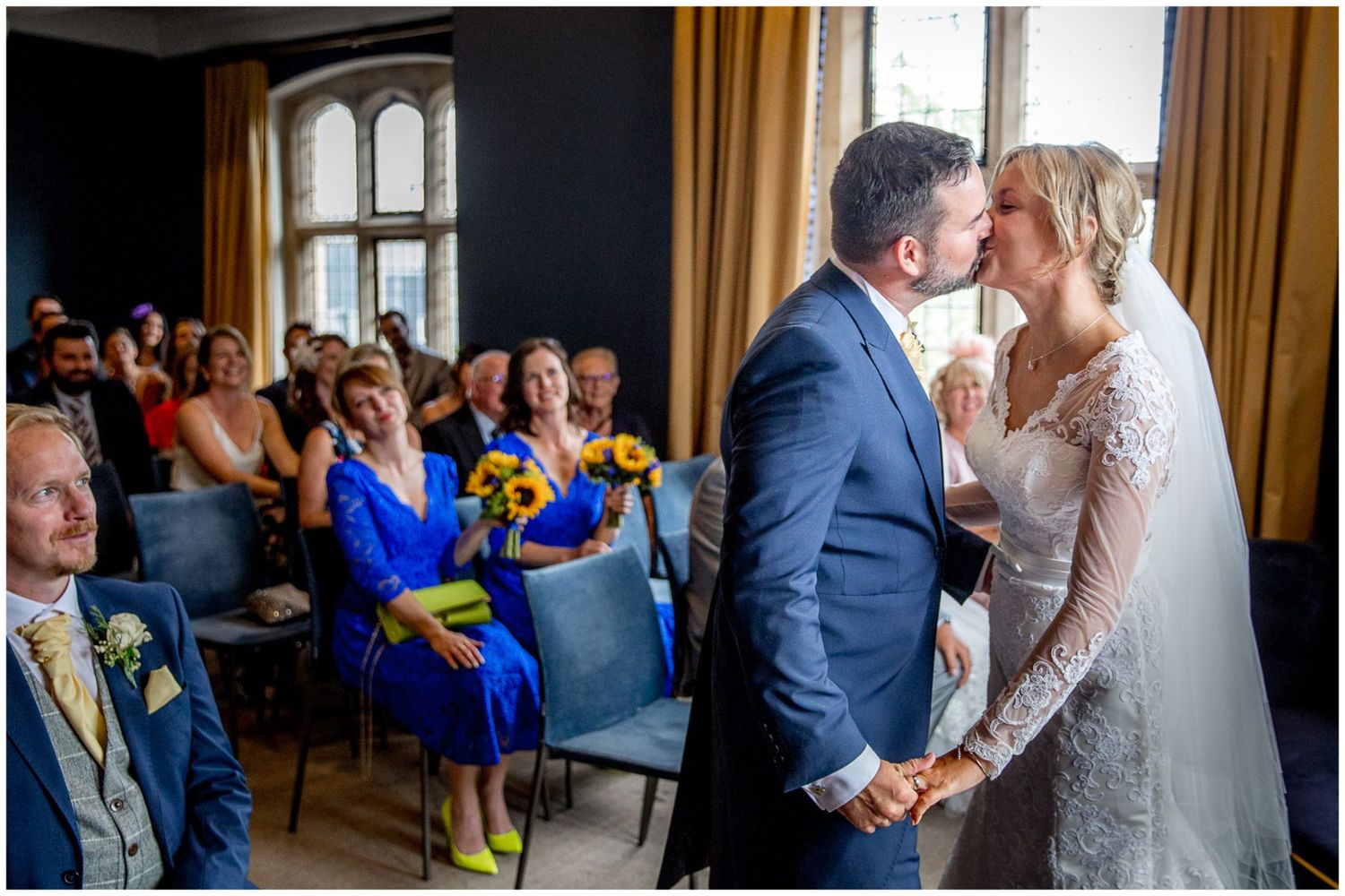 Couple sharing an intimate dance moment in a formal venue while guests look on during a celebration.