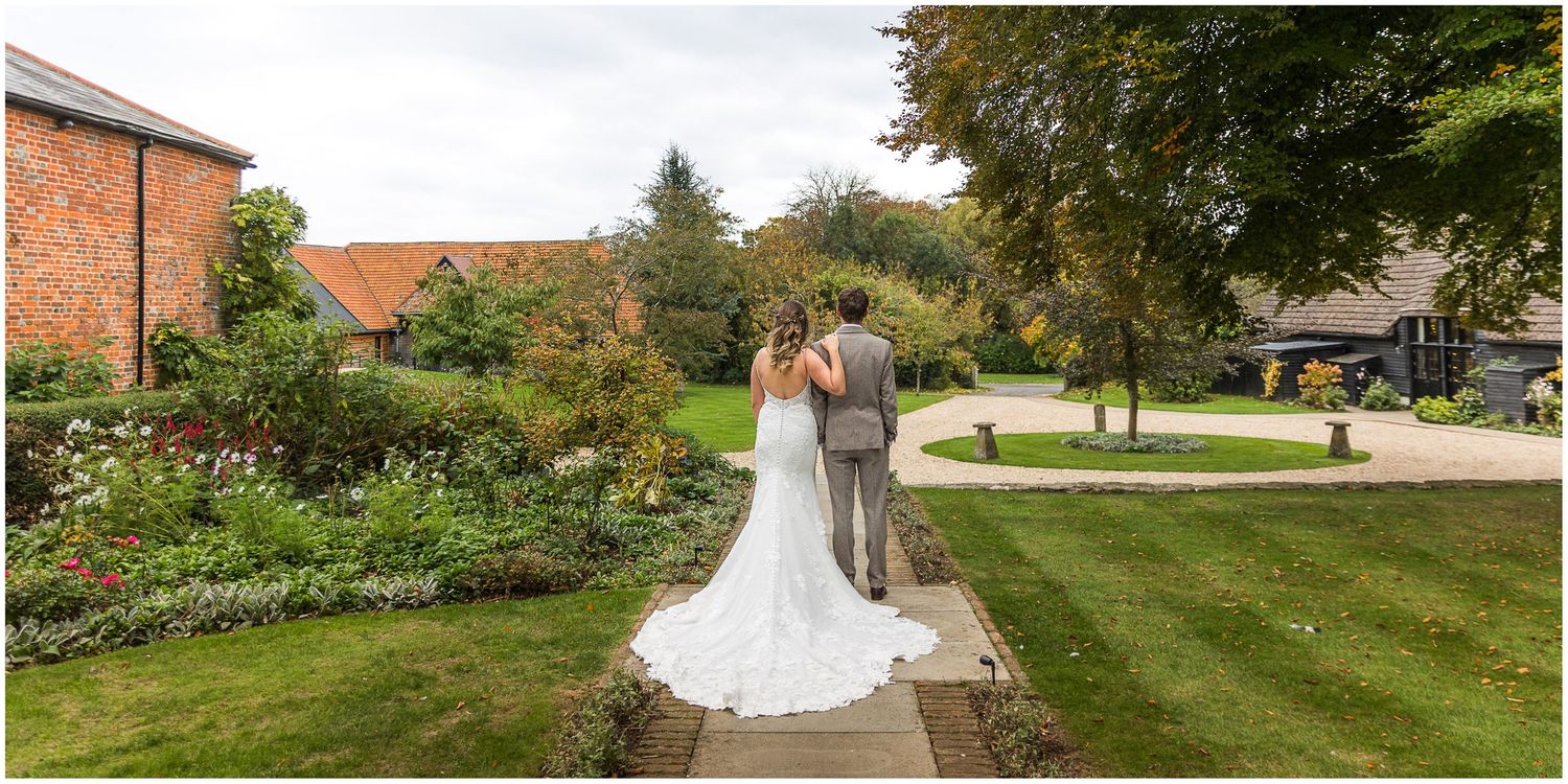 The bride and groom standing together for their wedding photography, facing the courtyard at Clock Barn wedding venue in Hampshire.