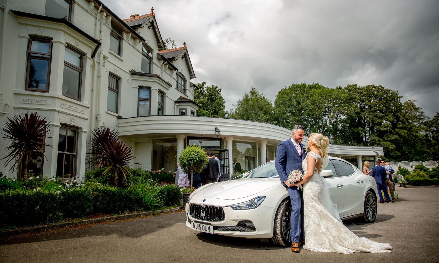 Panoramic view of a grand Victorian mansion exterior with wedding celebration on the grounds.