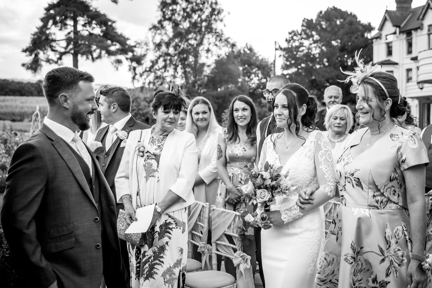 Wedding party celebrating outdoors with guests gathered around on a sunny day.