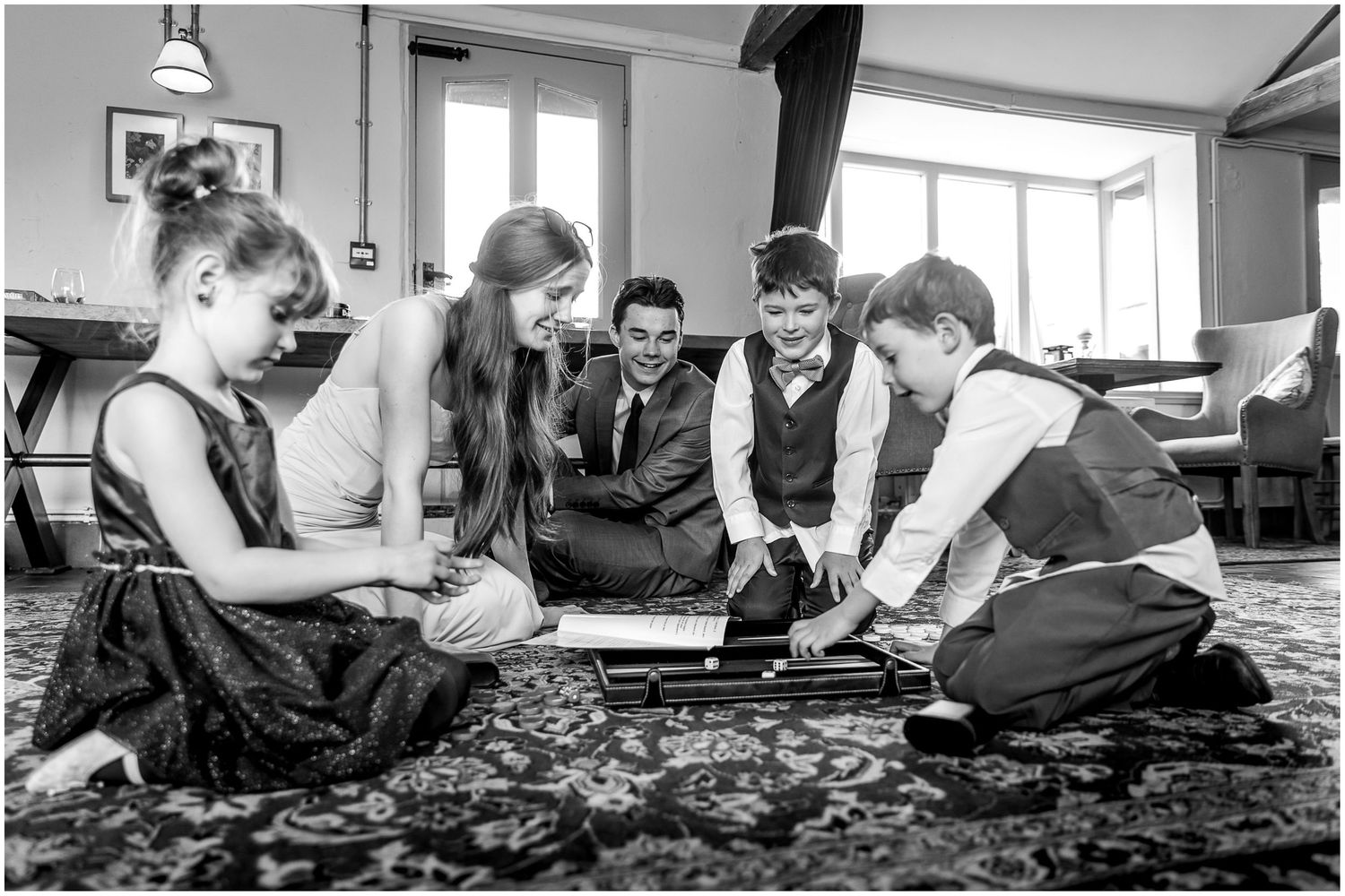 Group gathered around a carpet or rug on the floor during what seems to be a social gathering.