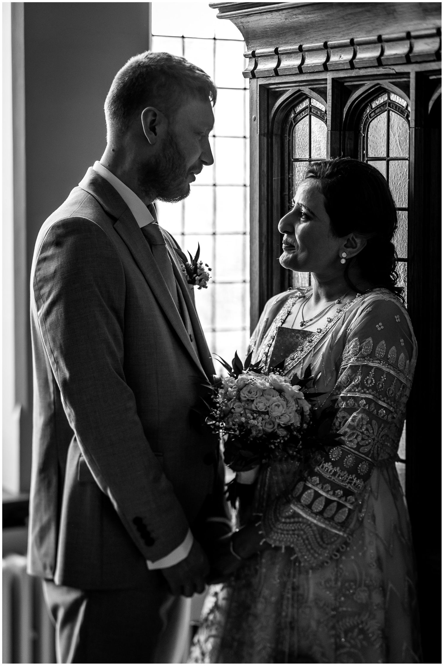 Dramatic black and white wedding portraits captured near ornate windows.