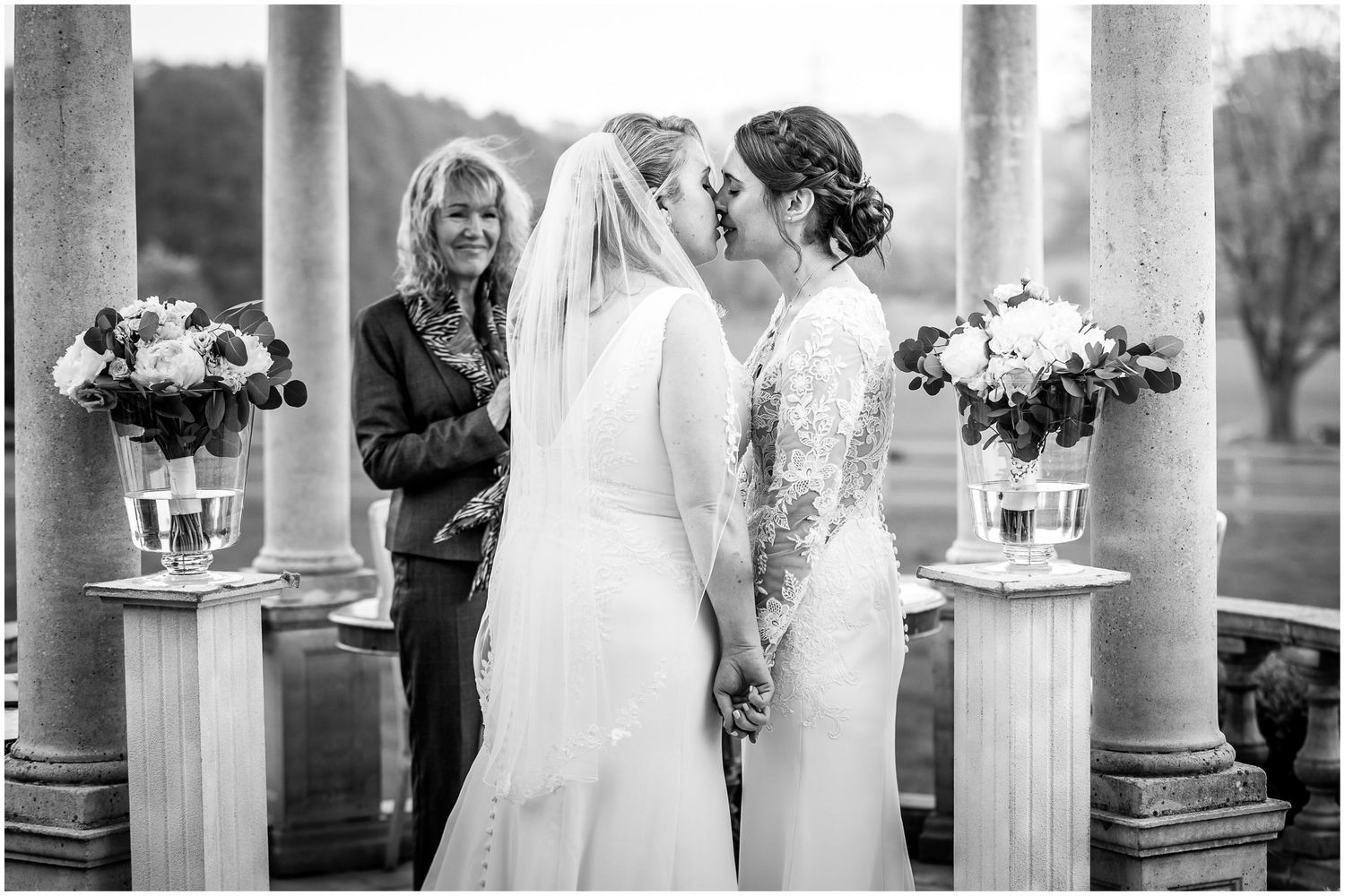 Black and white photo of a wedding ceremony taking place under an elegant columned structure.