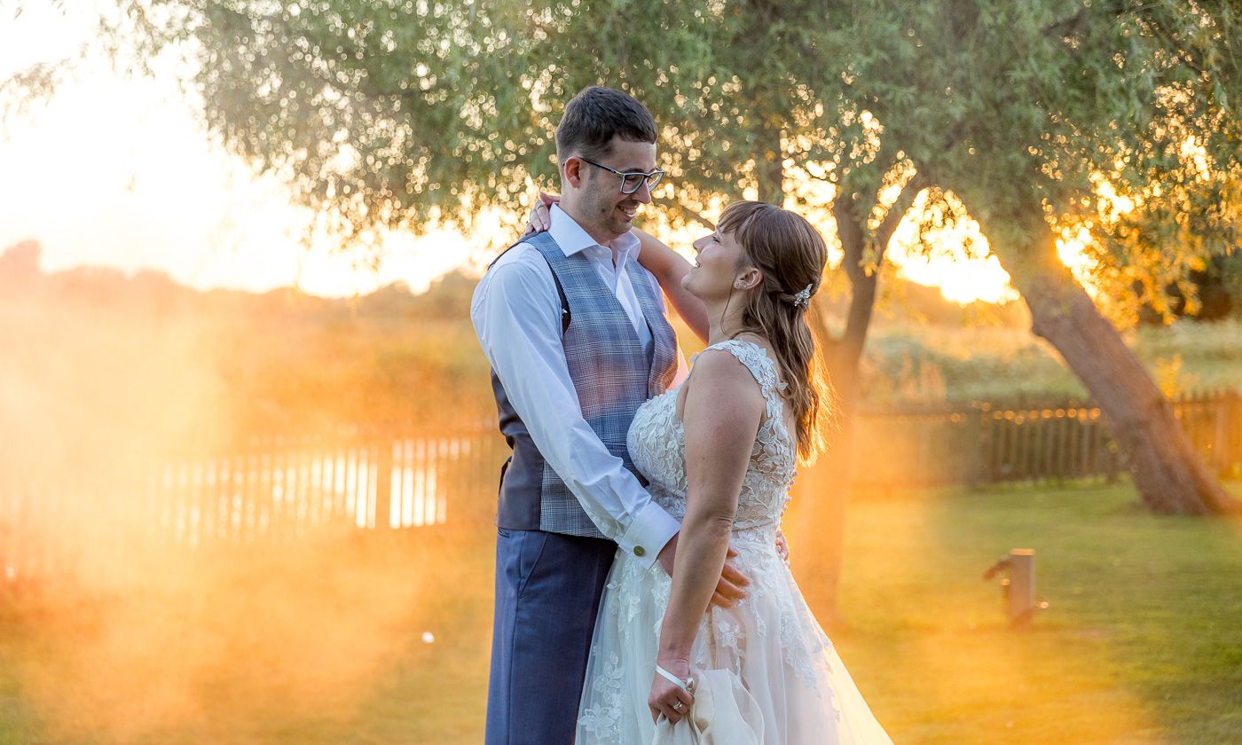 Romantic sunset portrait in garden with golden sunlight streaming through trees.
