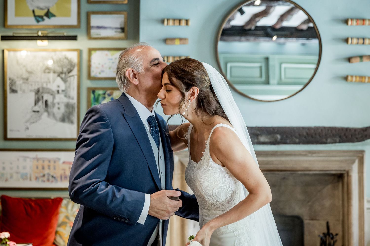 Elegant wedding scene in blue-walled room decorated with vintage artwork and mirrors.