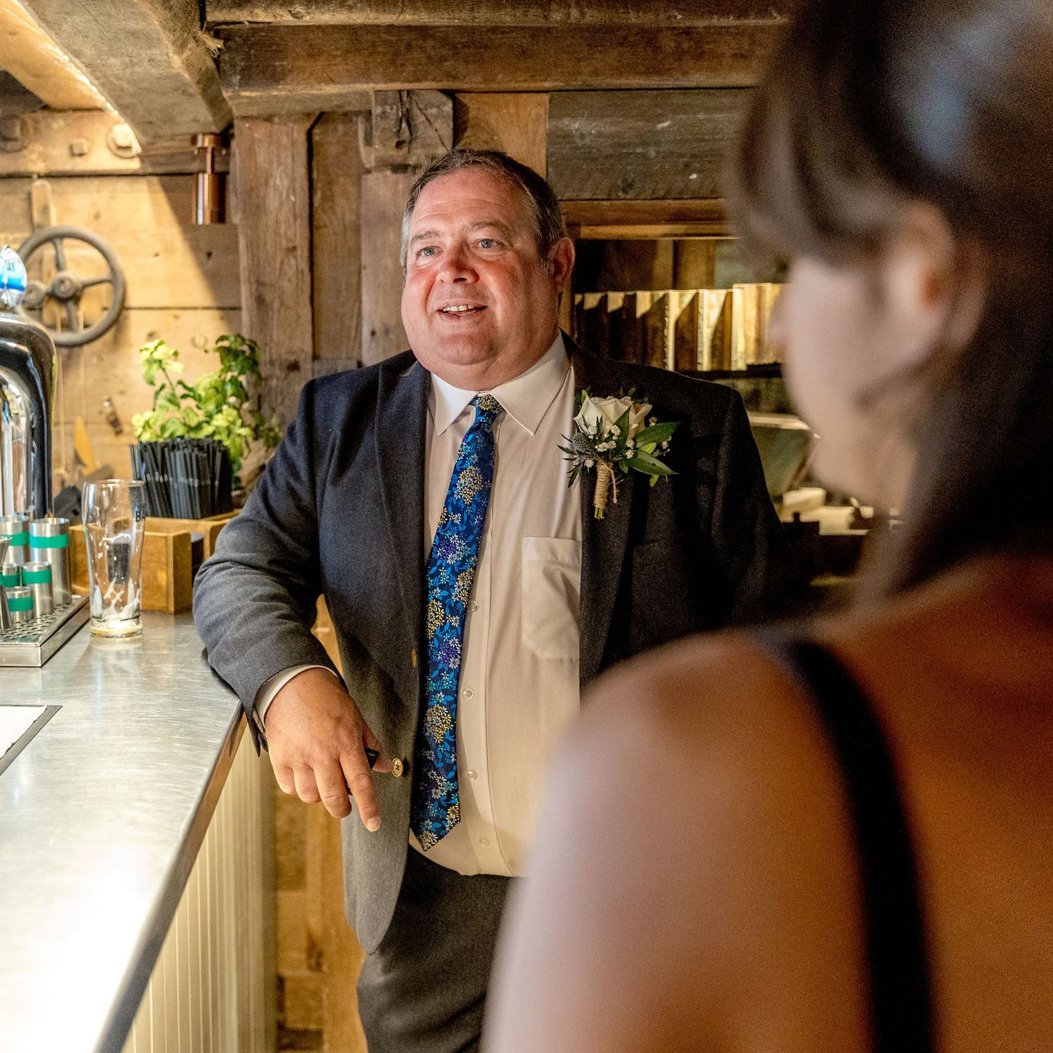 Guests engage in conversation at formal event in rustic indoor setting.