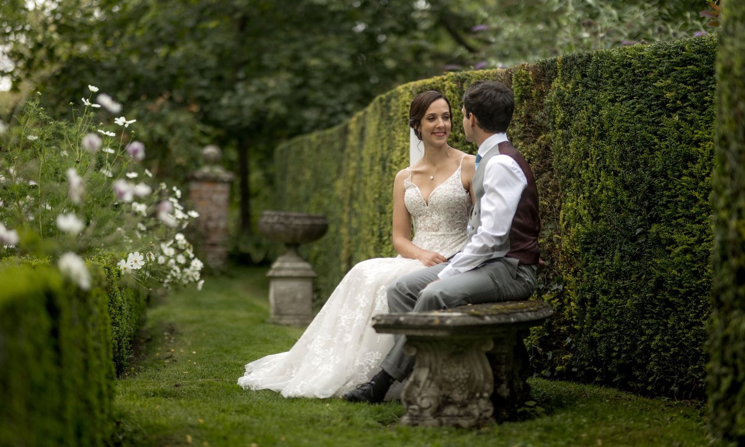 Romantic garden scenes with a wedding sitting among lush greenery and flowers in the gardens of Houghton Lodge in Hampshire