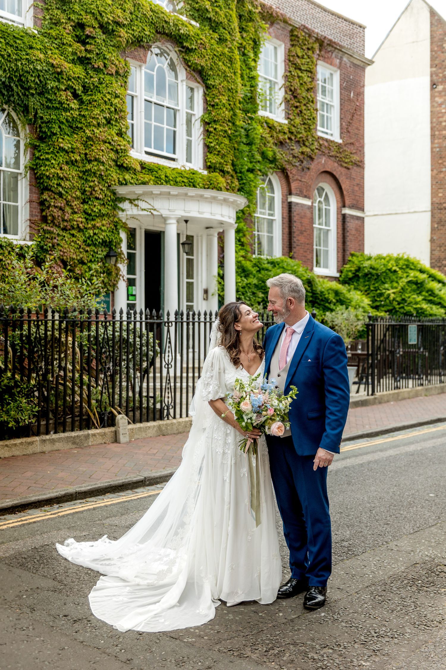 Couple poses for wedding photos outside an ivy-covered brick building.
