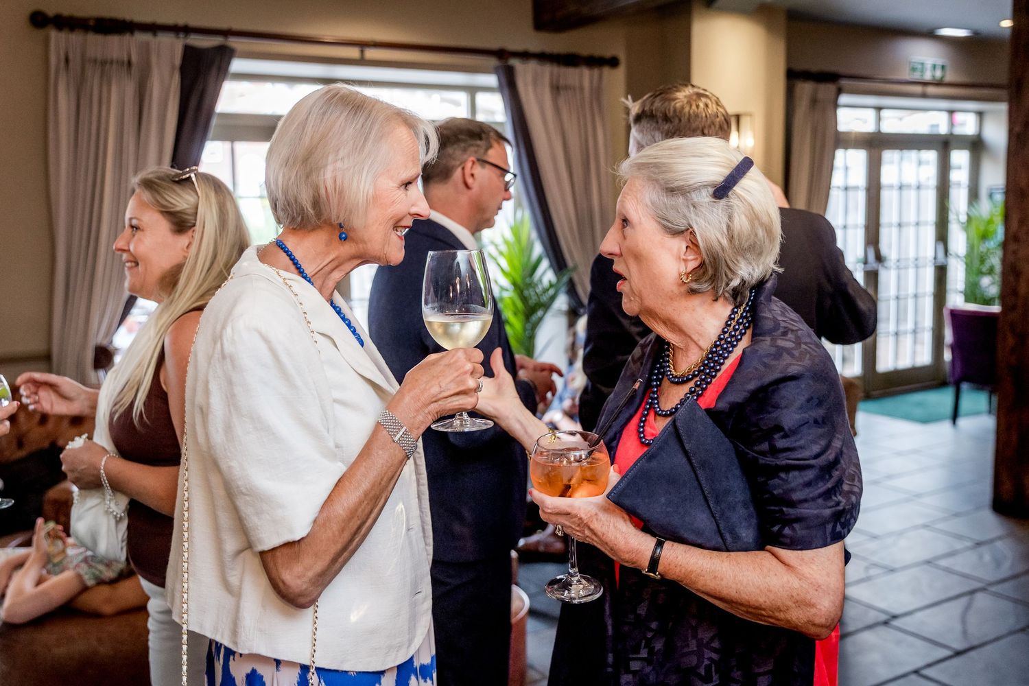 Candid moments of guests interacting at a formal indoor celebration.