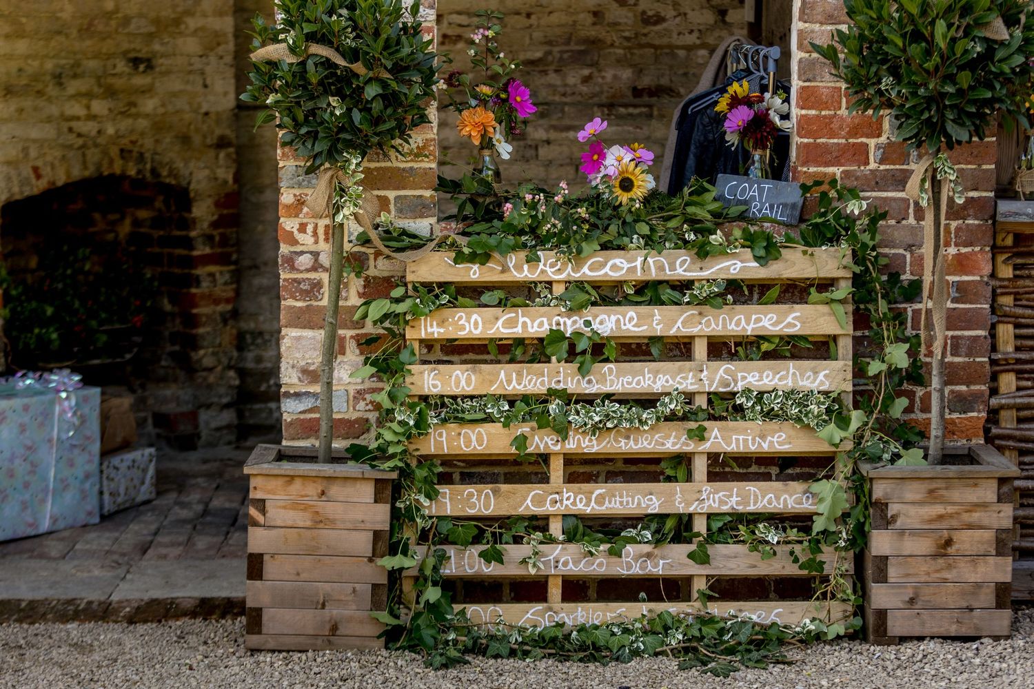 Rustic wooden pallet seating chart displays against weathered brick wall.