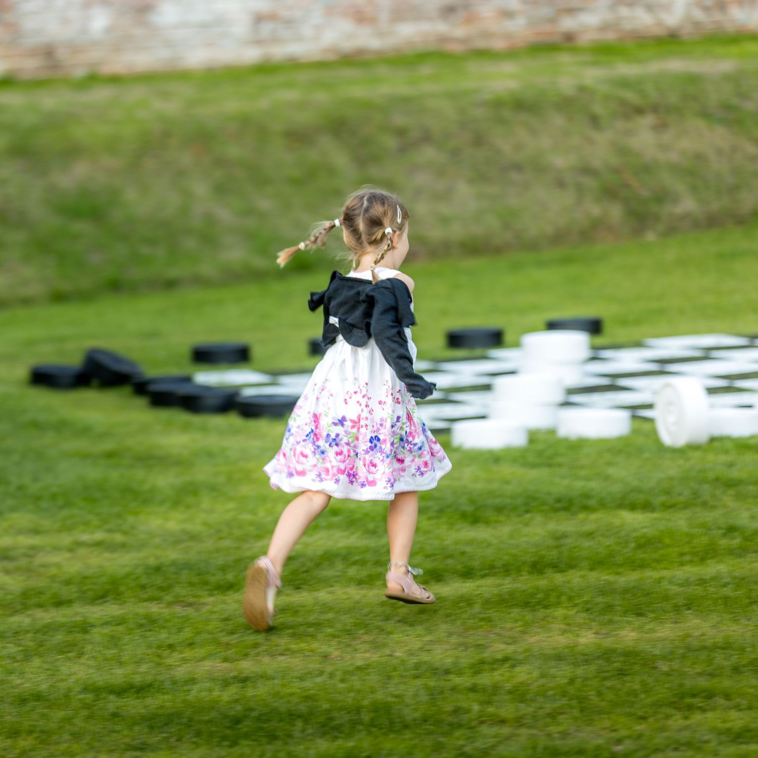 Child playing and running on grassy lawn during outdoor event.