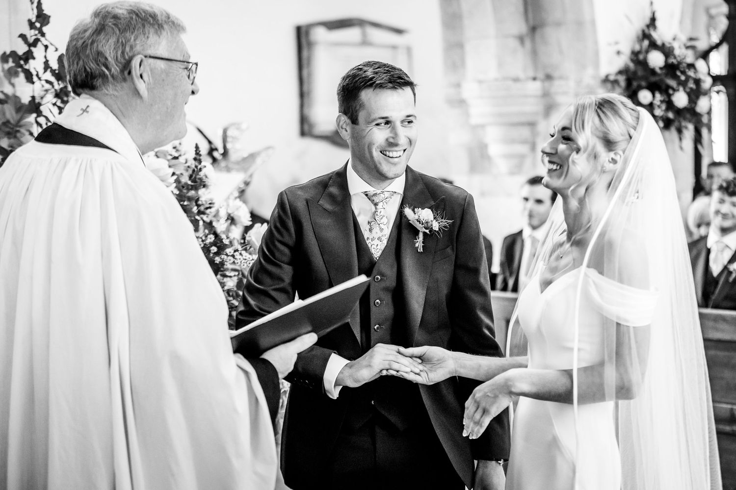 Black and white photo of wedding ceremony exchange at church altar.