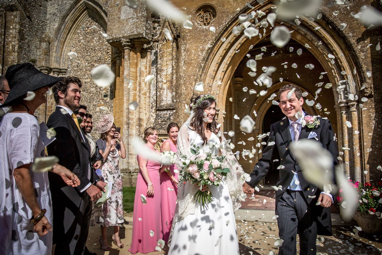 Wedding celebration at a historic stone church with confetti being thrown by guests.