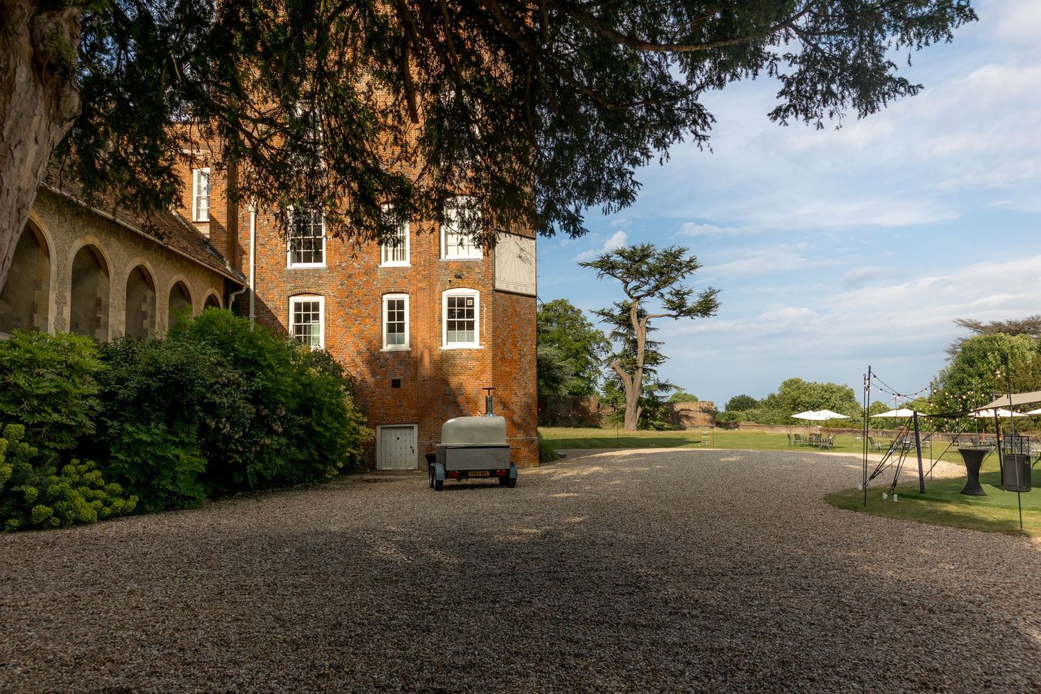 Wide angle view of historic manor grounds with gravel driveway and brick buildings.