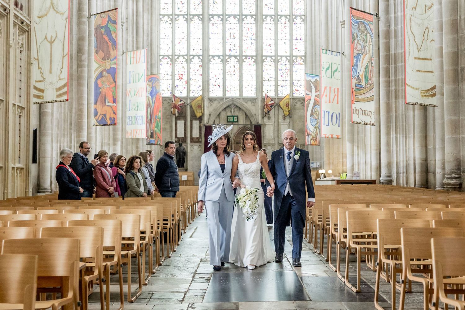 Long rows of wooden chairs line a grand cathedral aisle with towering Gothic windows and arches.