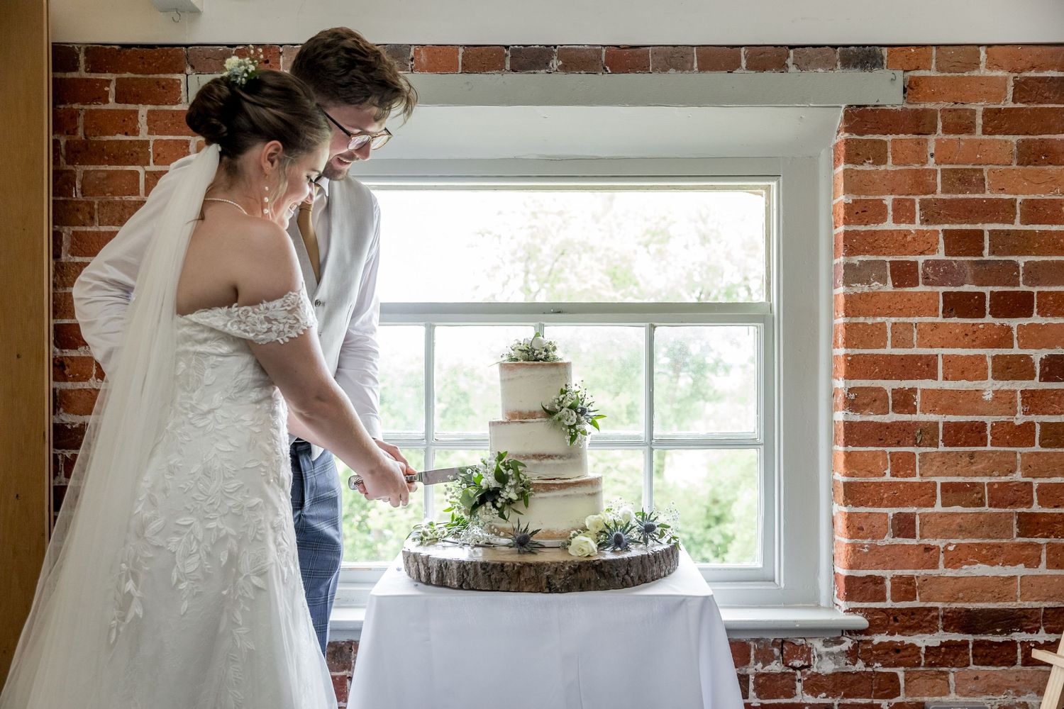 Wedding celebration in a light-filled room with exposed brick walls and elegant white trim.
