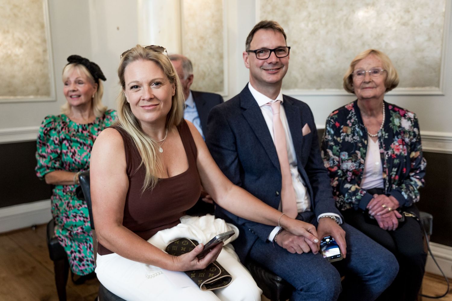 Wedding guests smile and socialize during a reception in an elegant venue.