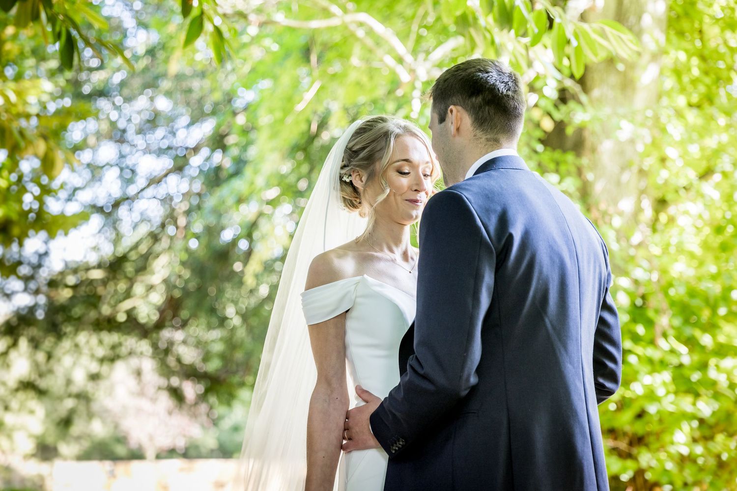 Romantic garden wedding portraits under lush green summer foliage.