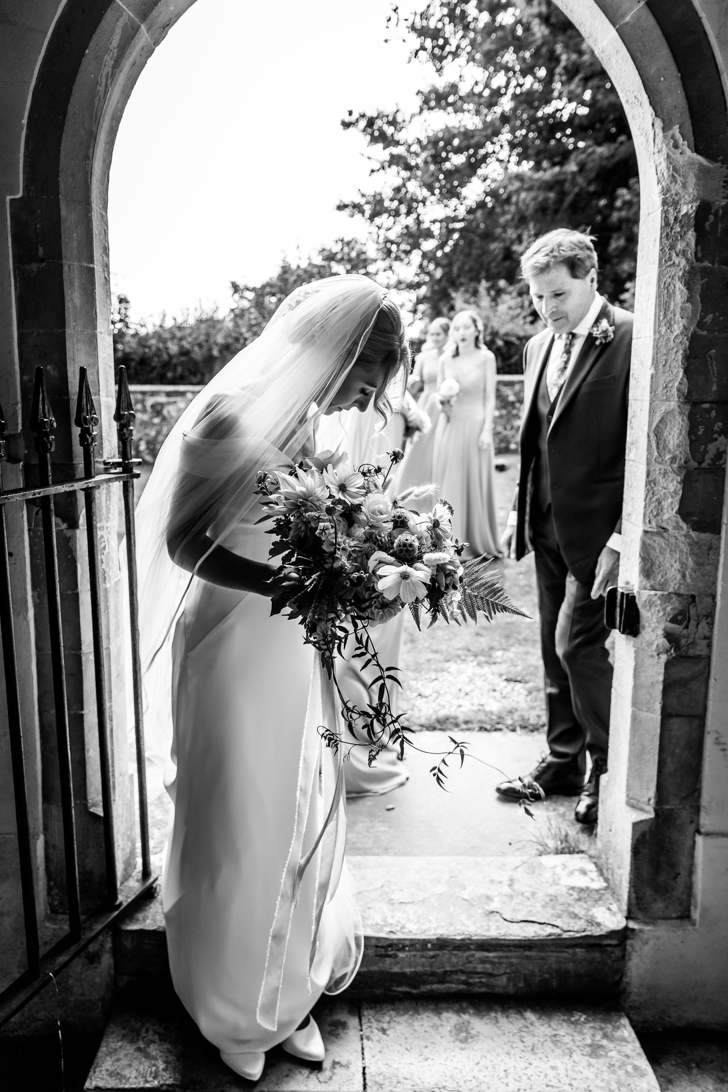 Black and white photos of wedding moments under stone church archway.