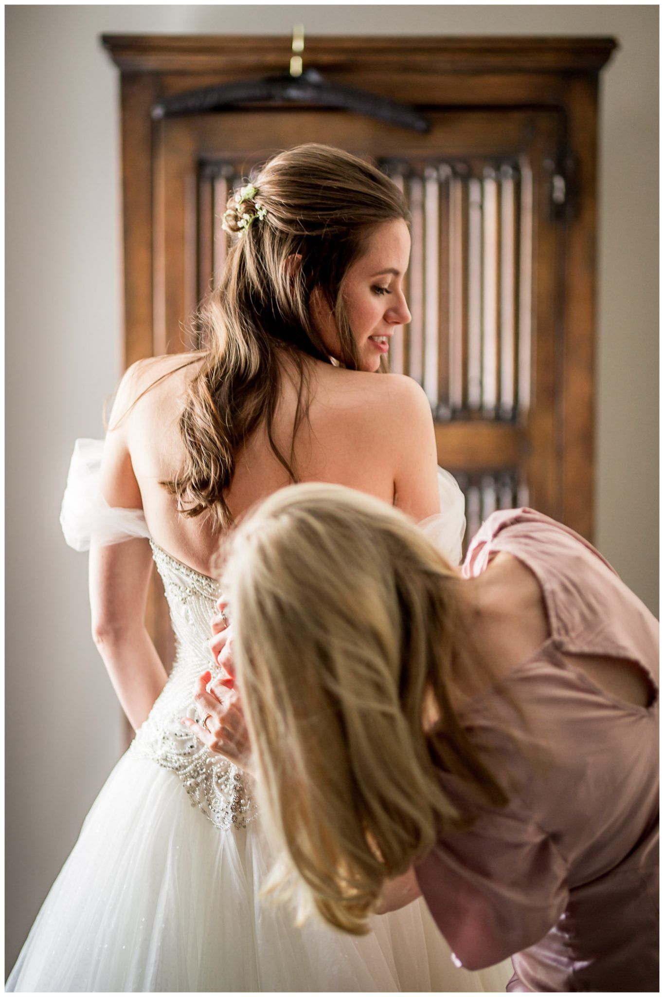 A bride in a white wedding gown shares an emotional moment during her wedding preparations.