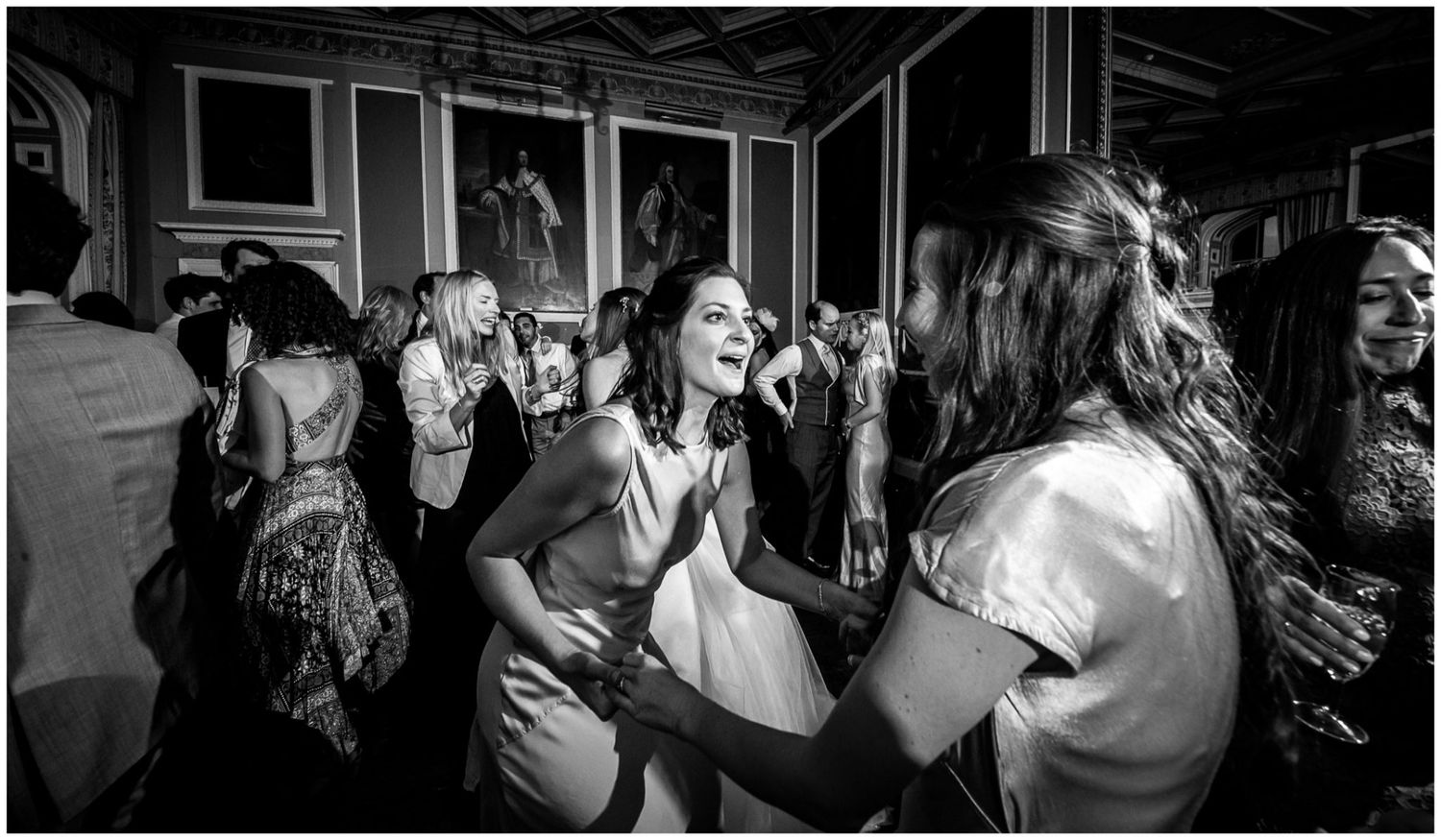 People dancing and enjoying themselves at a crowded party in a black and white photograph.