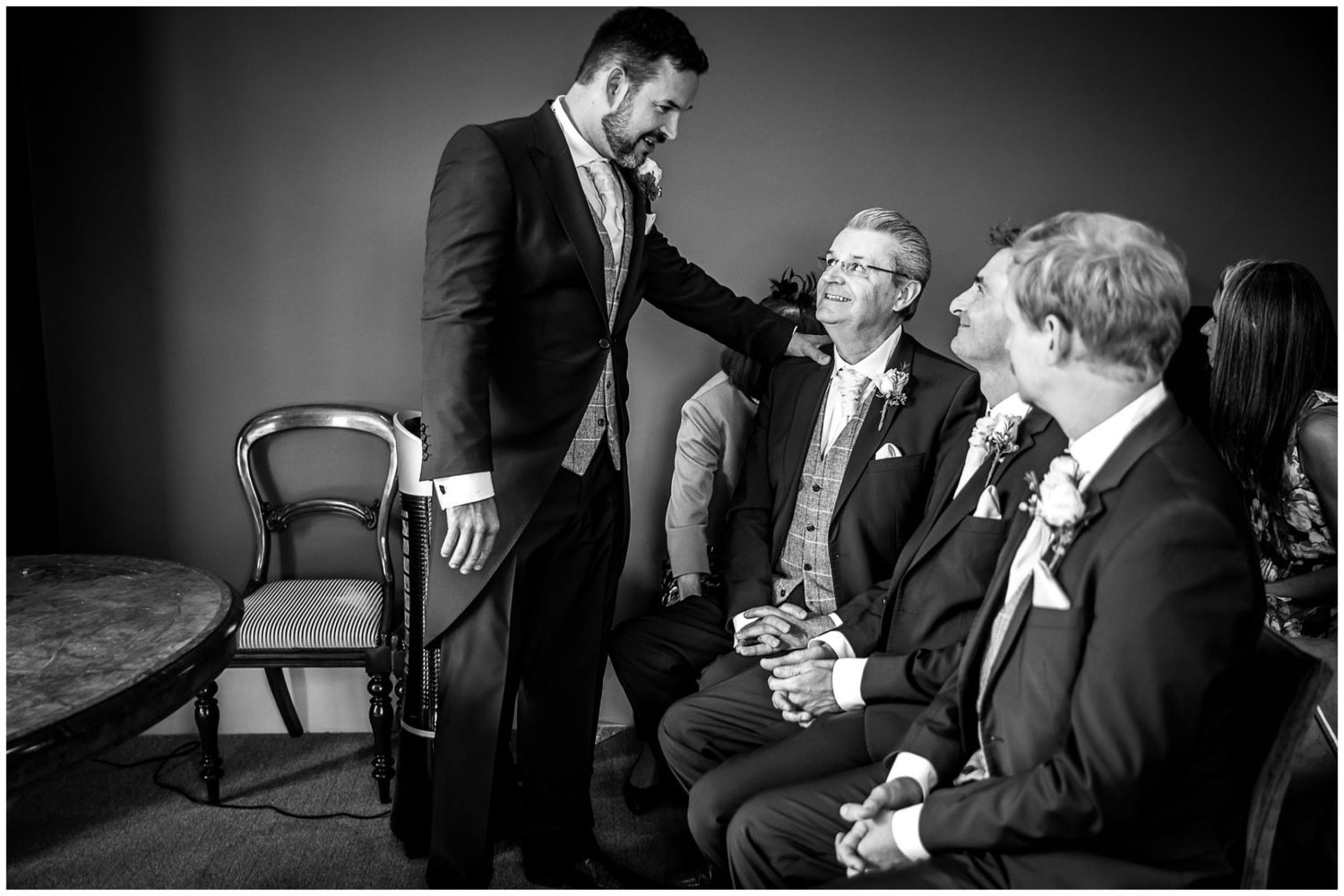 A series of black and white candid moments at a formal event showing people interacting and laughing together.