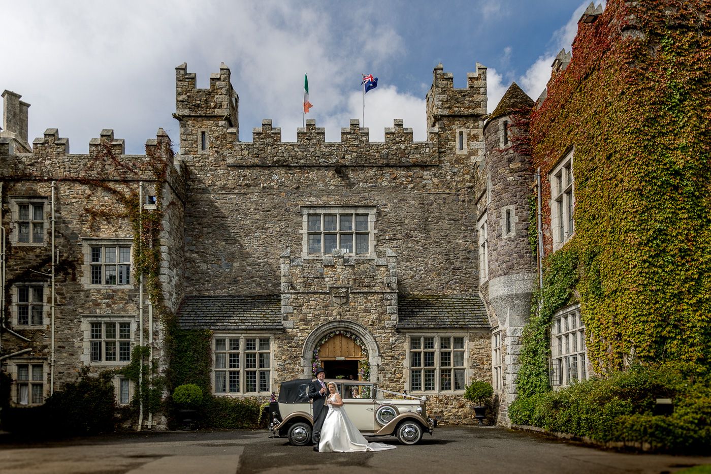 Historic stone castle exterior with ivy-covered walls and classic architecture on a cloudy day.