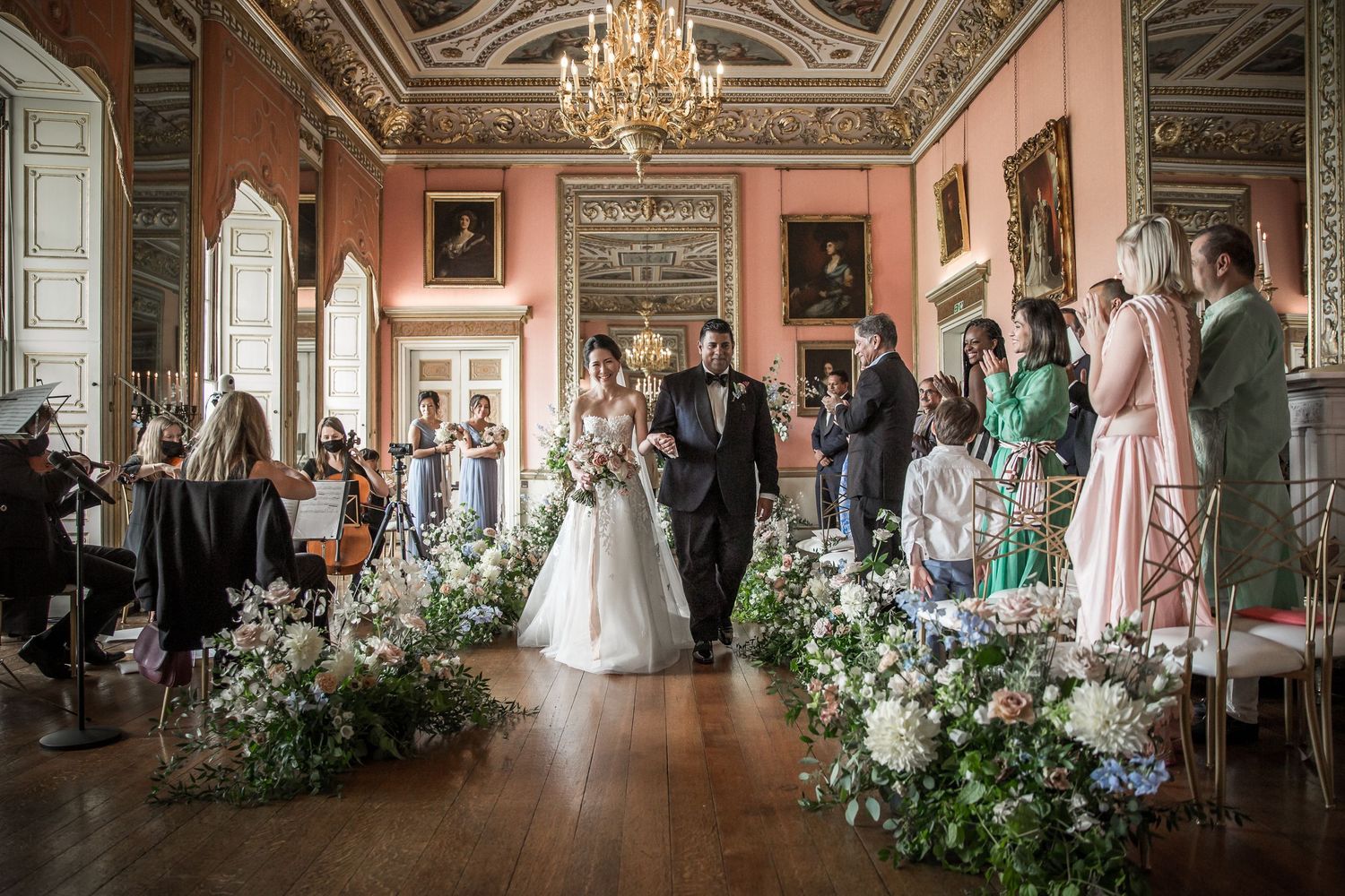 Elegant wedding ceremony setup in a grand historic room with chandeliers and floral arrangements.