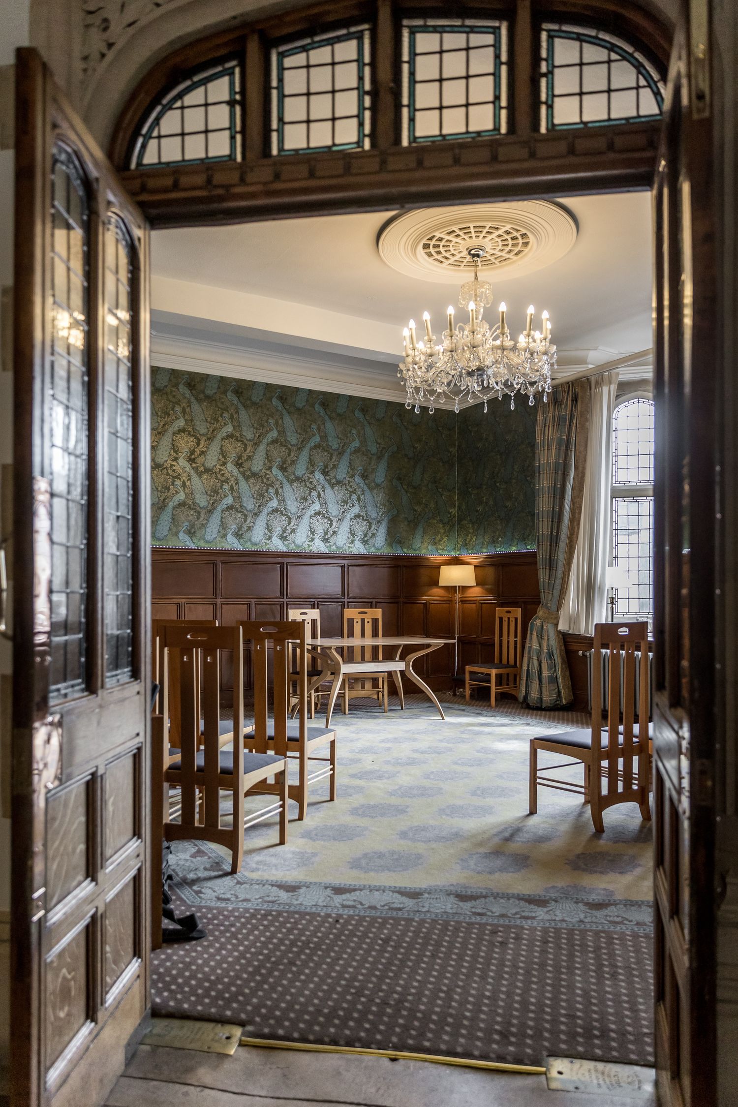 Elegant reception room with crystal chandelier, wood paneling, and large windows.