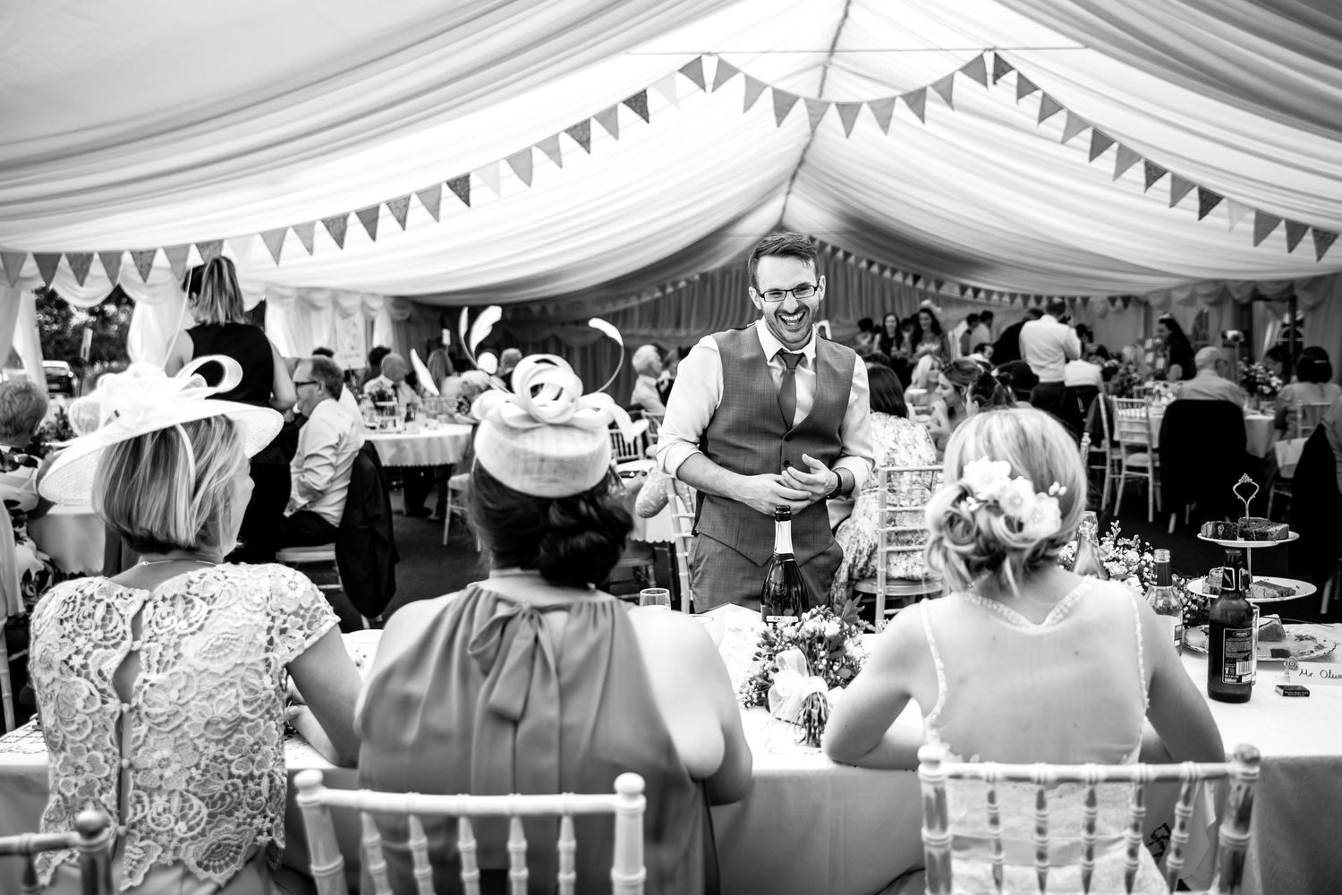 Wedding reception tent decorated with bunting and filled with celebrating guests.