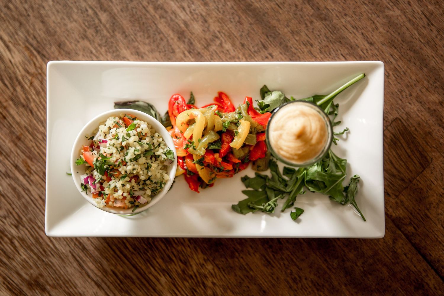 Elegant appetizer plates with colorful hors d'oeuvres and garnishes arranged on a rustic wooden table.