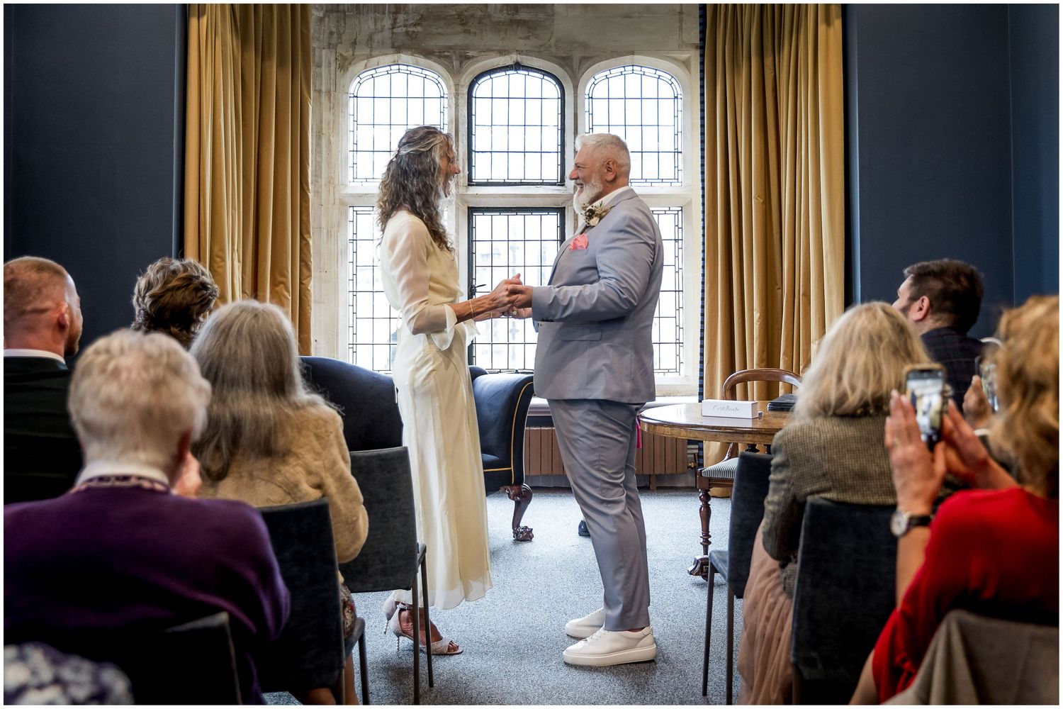 Wedding couple face each other in front of the window of the Castle Room in Winchester