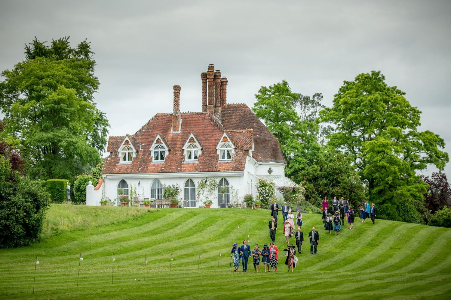 Houghton Lodge wedding reception with wedding guests walking down the hill from the house to the marquee