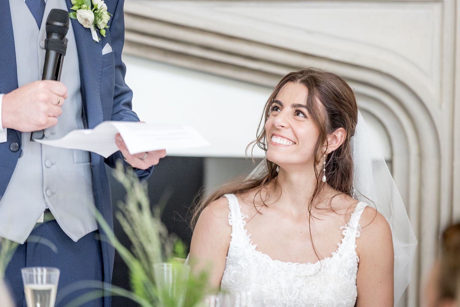 Guests seated at elegant wedding reception tables with white linens and floral centerpieces.