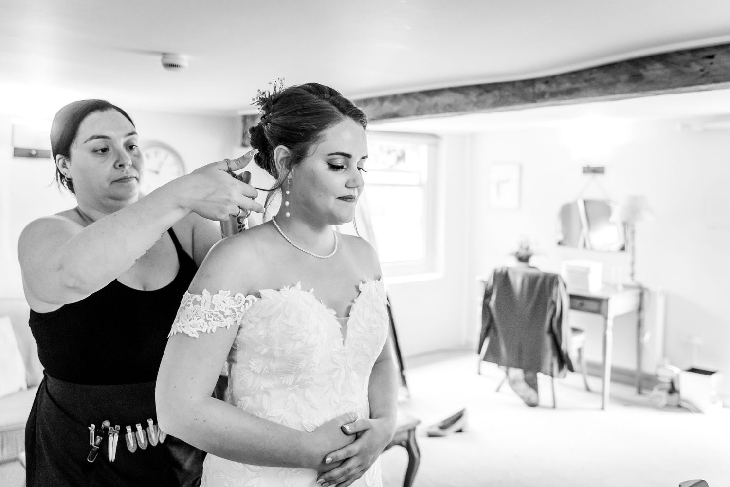 Wedding party members help with preparations in a bright room before the ceremony.