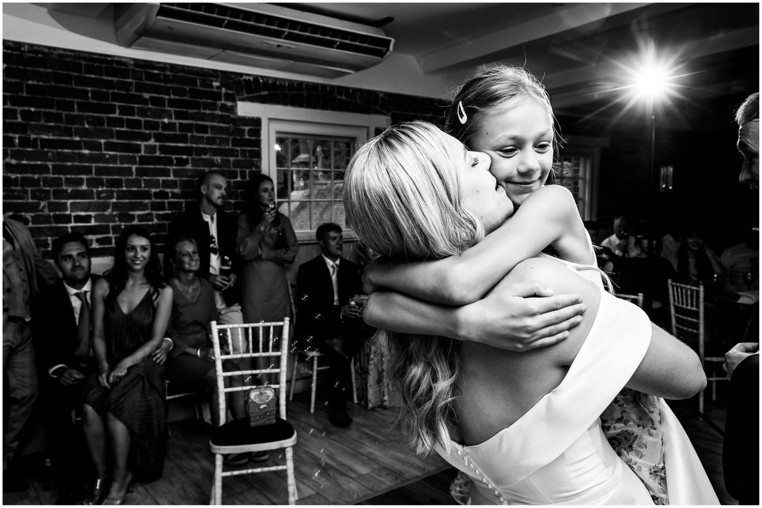 Black and white photos of wedding guests embracing during emotional reception moments.