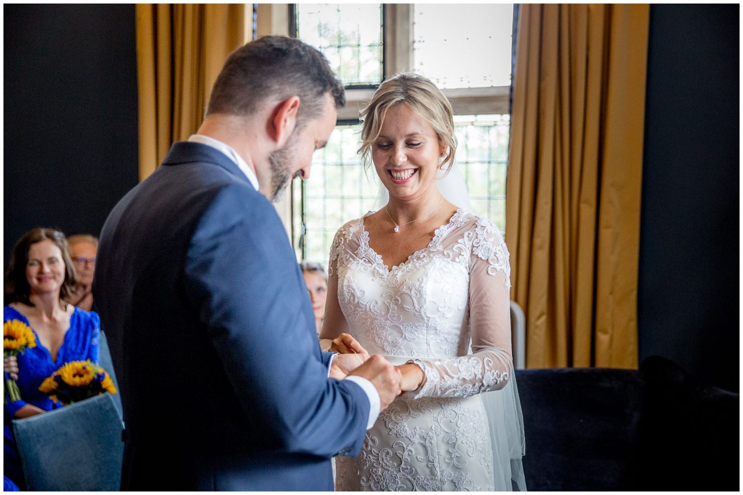 Wedding guests celebrate and dance together in an elegant venue with warm lighting and golden curtains.