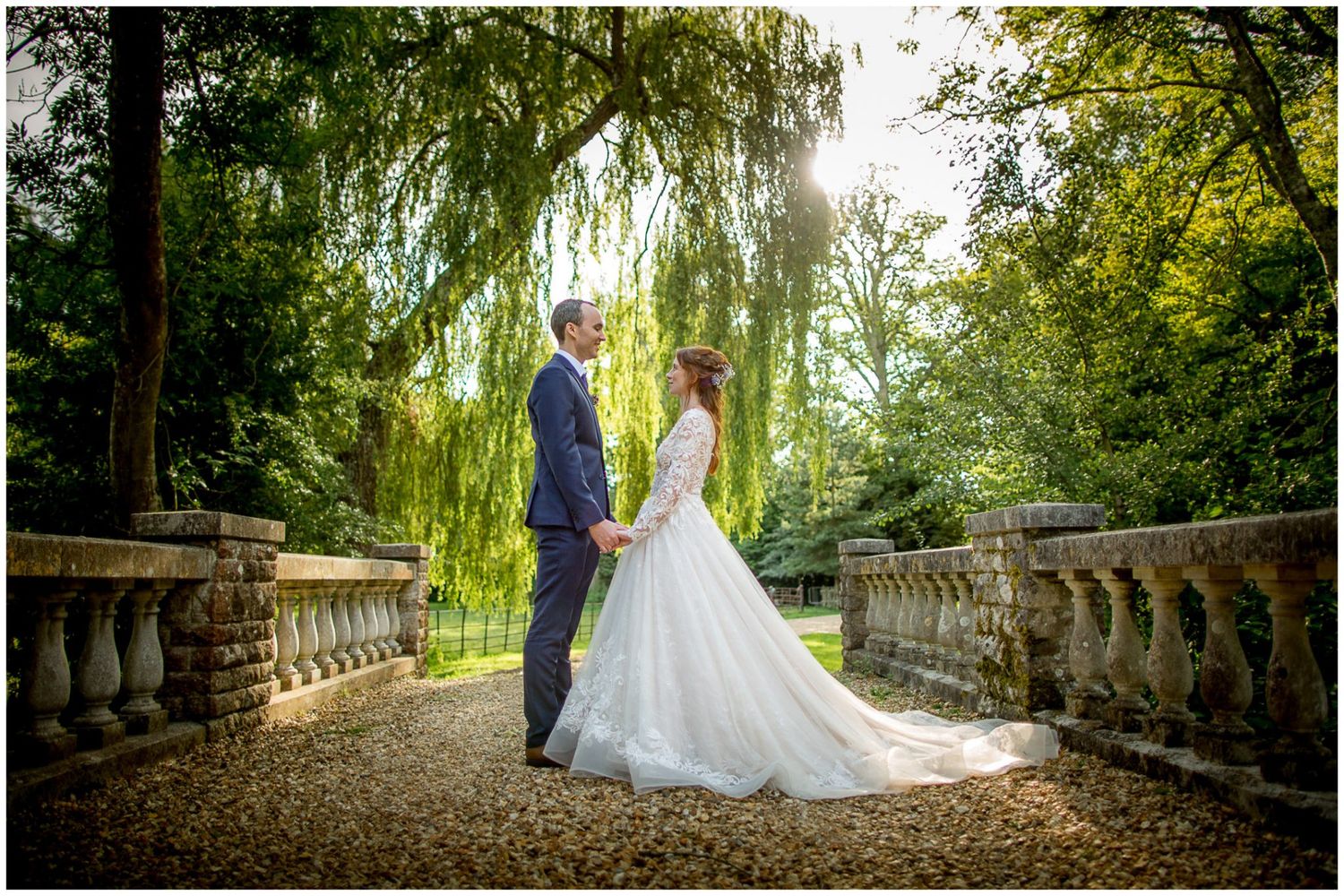 A romantic wedding photo session on a stone bridge surrounded by lush green trees and natural scenery.