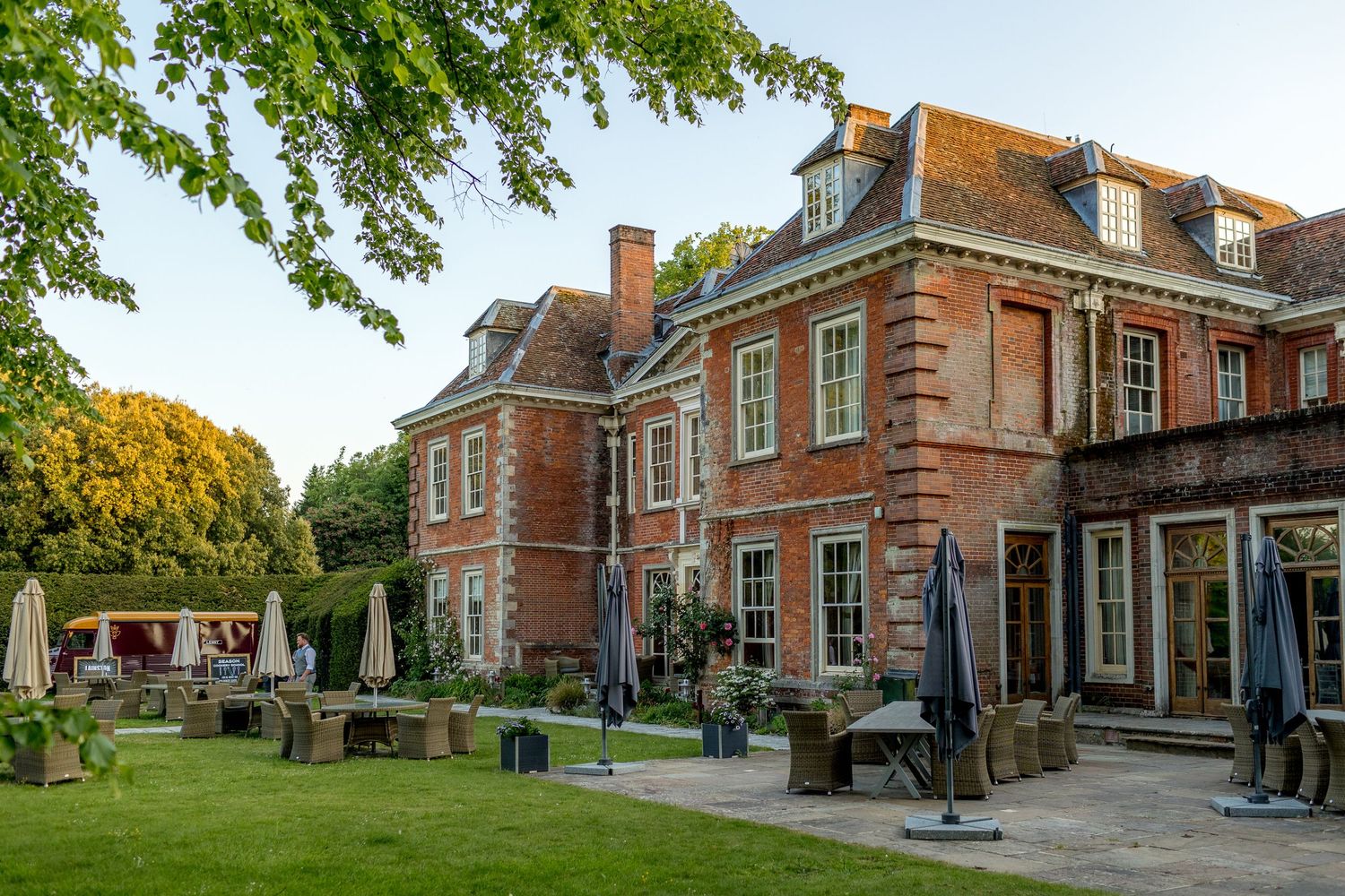 Exterior view of a grand historic red brick manor house with manicured grounds.