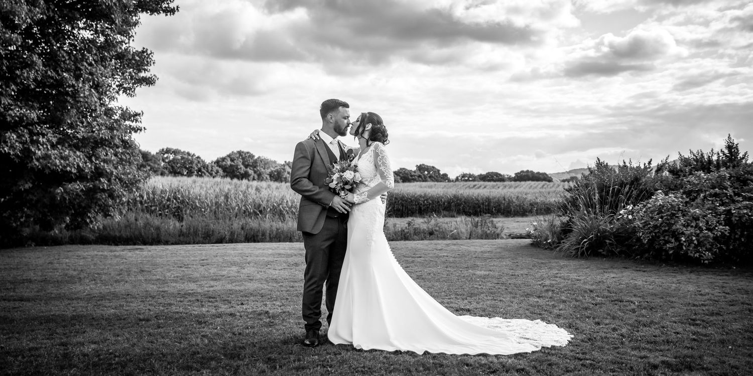 Dramatic black and white wedding photos taken in an outdoor setting with cloudy skies.