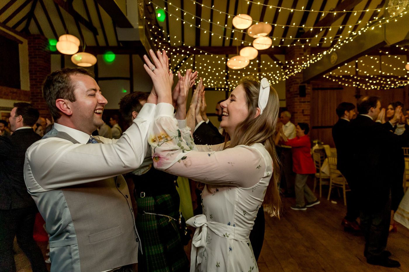 Wedding reception dance floor with string lights and couples dancing.