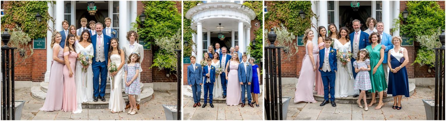 Wedding party poses in front of white columns and greenery.