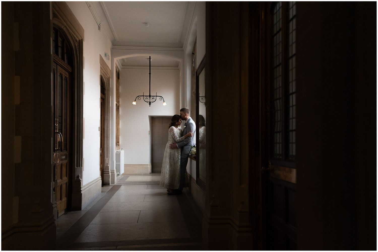 Long elegant hallway with arched windows and dramatic lighting in a historic building.