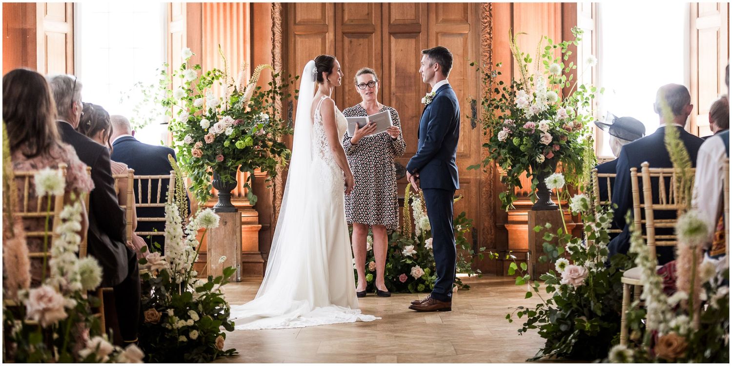 Colour photograph of the bride and groom making their vows in the main hall of Walhampton School in the New Forest