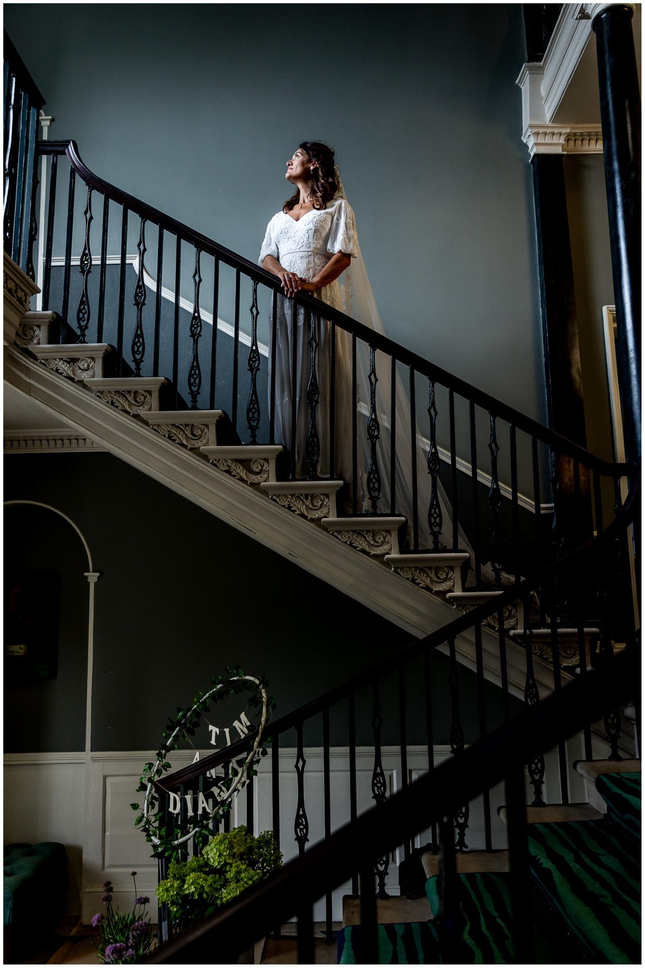 Elegant staircase with wrought iron railings creates dramatic shadows in an interior wedding venue.