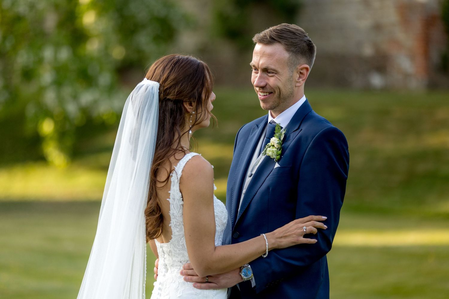 Wedding couple shares intimate moment in sunlit garden setting.