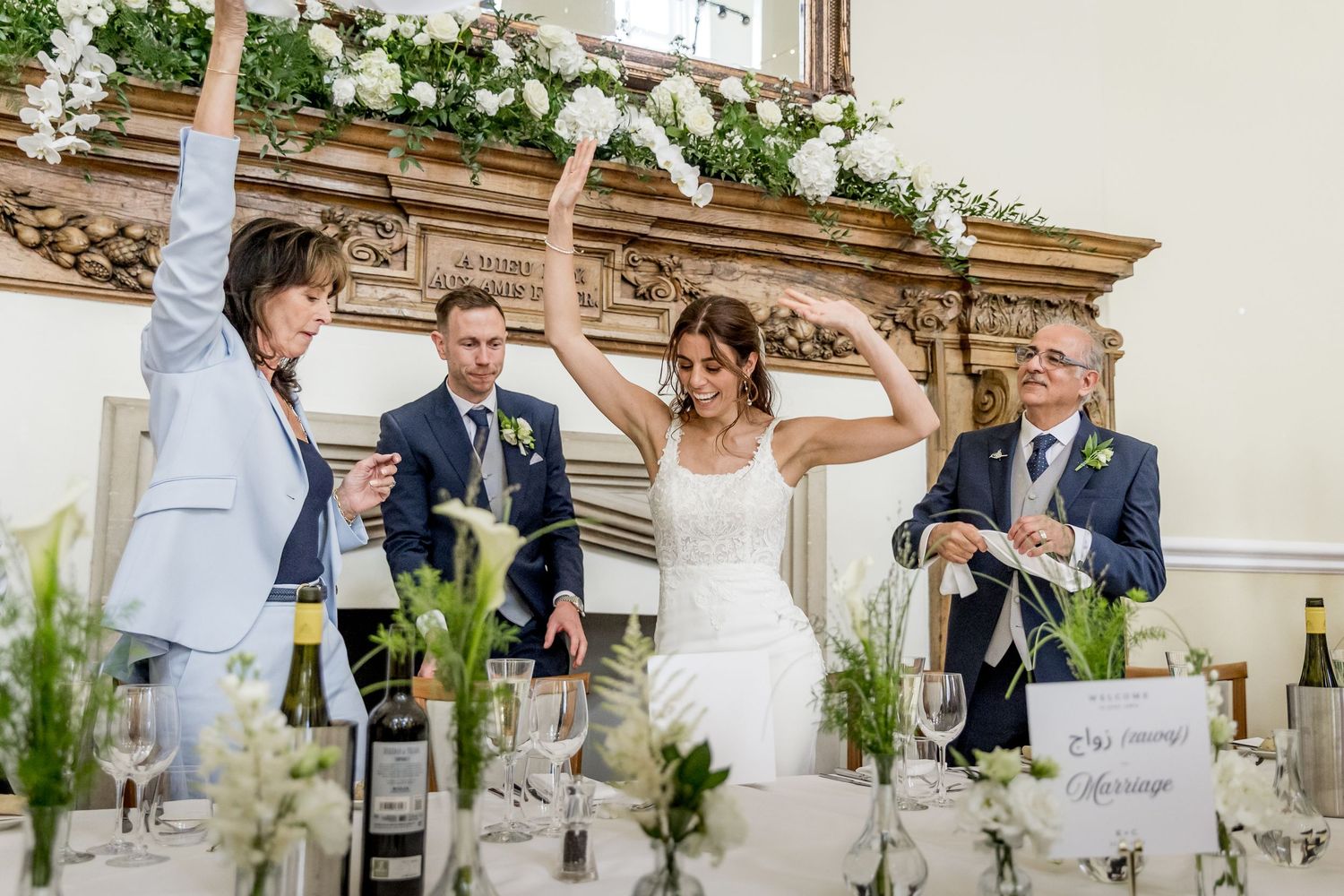 Wedding guests celebrate during an outdoor reception at an elegant venue with ornate architectural details.