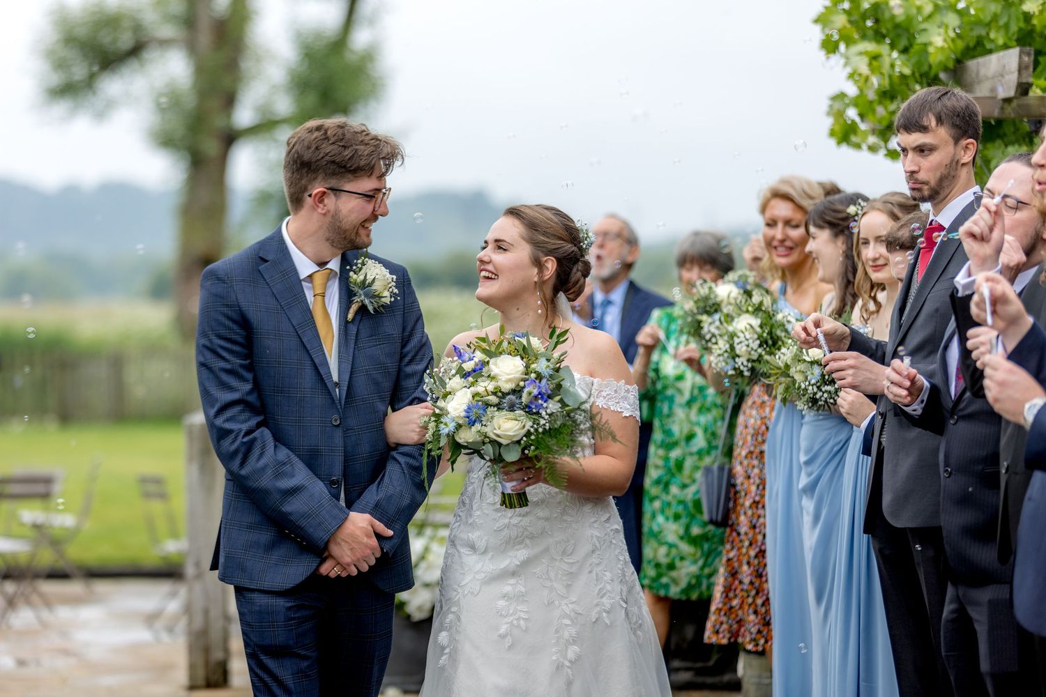 Elegant outdoor wedding reception with guests in blue and green attire.
