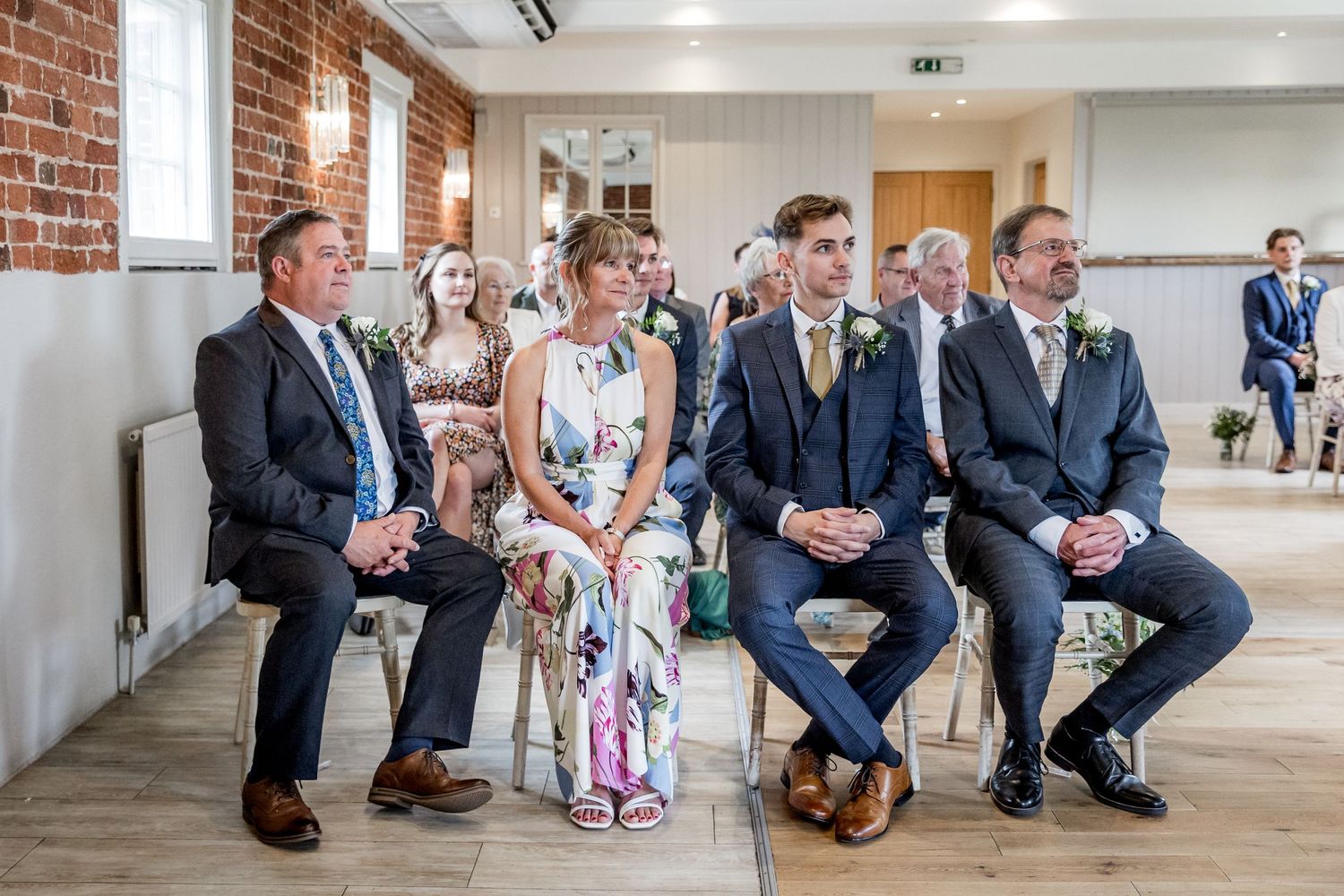Wedding party members arranged in a line against exposed brick walls in an industrial-chic venue.